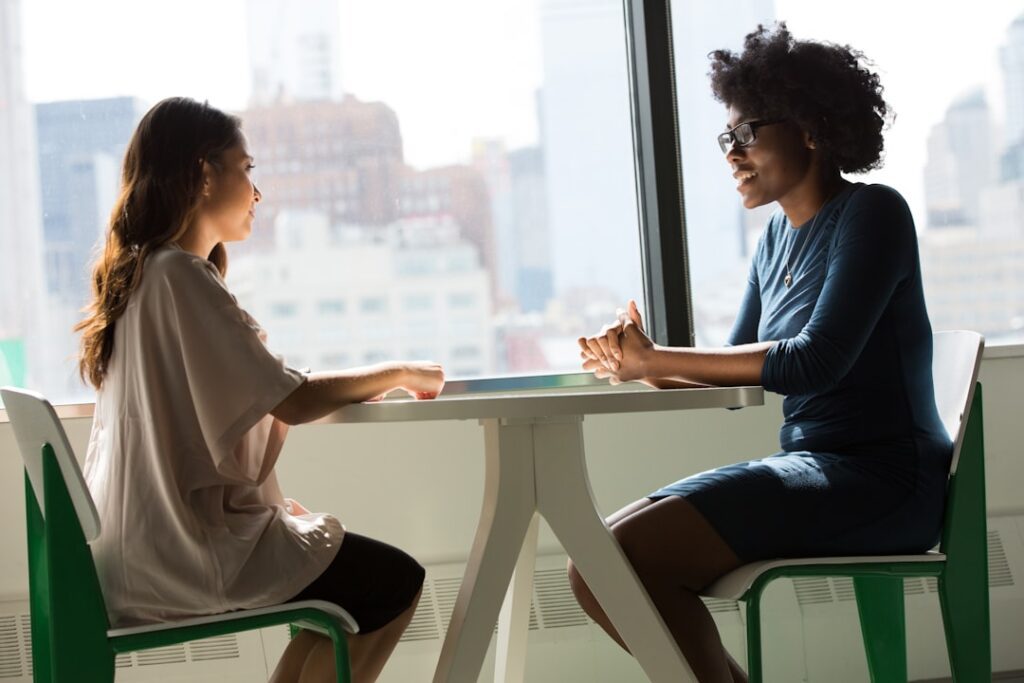 Two women sitting beside a table having a coaching conversation
